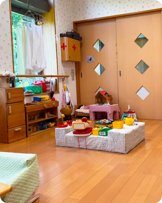 ままごと用のミニキッチンやおもちゃのレジスター、小さなテーブルなどが整然と並べられた病児保育室の室内の様子
