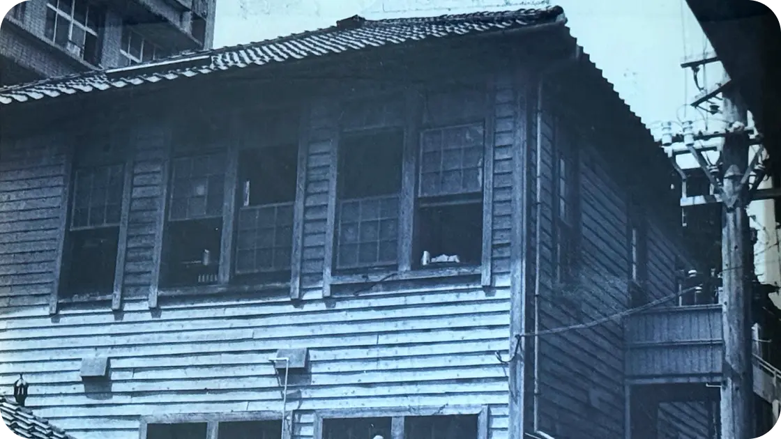 過去の歴史を感じさせる、2階建ての古い木造建築物の外観写真