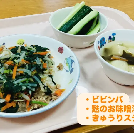 トレイに載せられた、ビビンバ、麩のお味噌汁、きゅうりスティックの給食メニューの様子