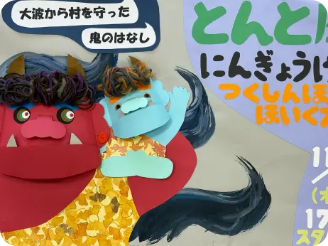 保育園の壁に飾られた、赤鬼と青鬼の手作りペーパークラフトと、行事を告知する手書きのポスター