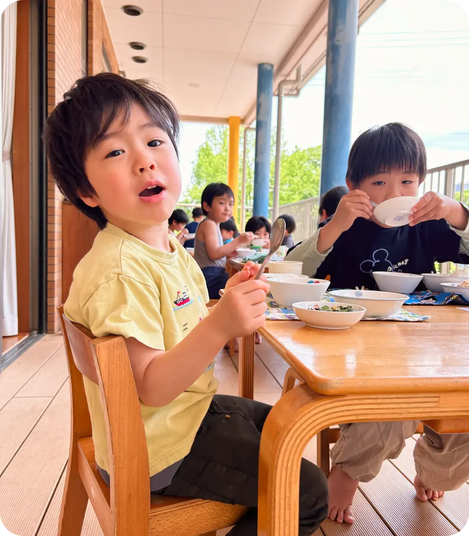 日当たりの良いテラスに並べられたテーブル席で、給食を食べる子どもたちの様子